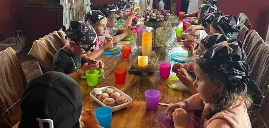Schulanfänger als Piraten verkleidet bei Piratenessen an einer langen Tafel