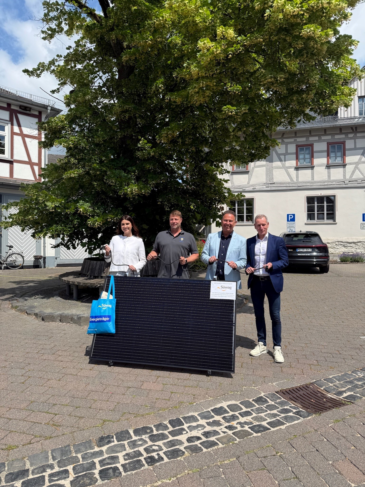 Bürgermeister Roland Hörster und Bauhofleiter Lars Werner übernehmen das Süwag-Balkonkraftwerk von Thomas Fösel und Tamara Savic