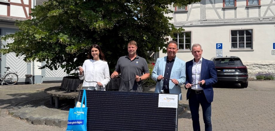 Bürgermeister Roland Hörster und Bauhofleiter Lars Werner übernehmen das Süwag-Balkonkraftwerk von Thomas Fösel und Tamara Savic