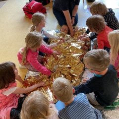 Kinder betreuen im Erste-Hilfe Kurs eine verletzte Person