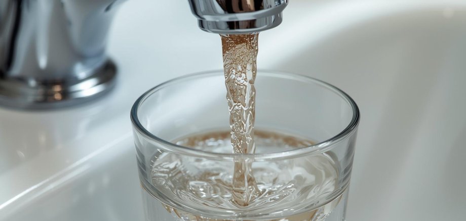 Eingetrübtes Trinkwasser Nahaufnahme eines Wasserhahns, aus dem leicht trübes Wasser kommt. darunter ist ein Glas mit Wasser zu sehen.