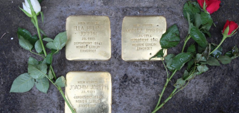 Drei neu verlegte Stolpersteine zum Gedenken an Ella Helene, Moritz Joseph und Joachim Joseph, geschmückt mit Rosen.