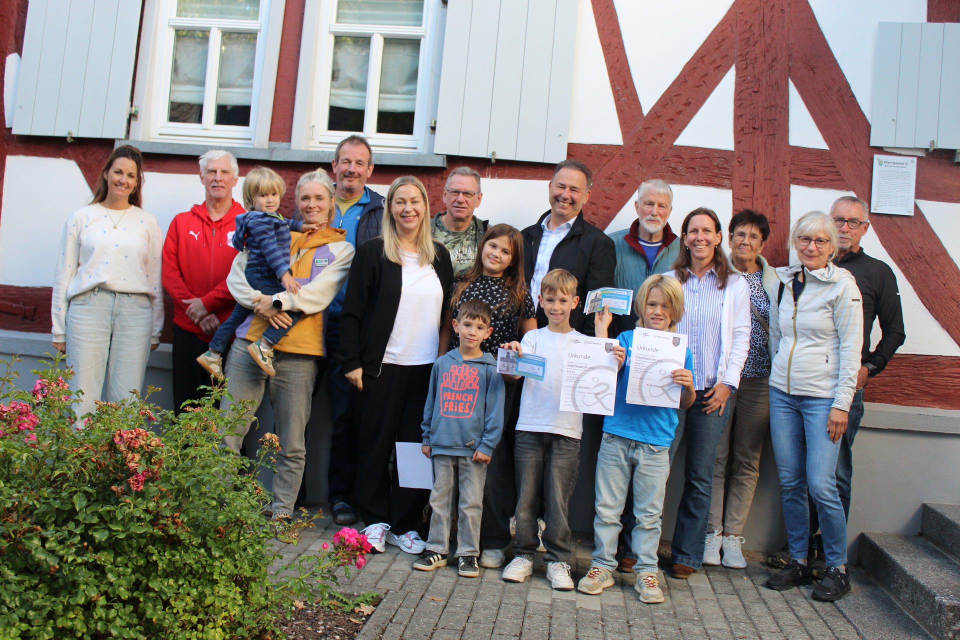 Gruppenfoto der Teilnehmerinnen und Teilnehmer des Waldsolmser Stadtradelns Gruppenfoto der Teilnehmerinnen und Teilnehmer des Waldsolmser Stadtradelns mit Kindern und Erwachsenen vor einem Fachwerkhaus. Einige halten Urkunden und Auszeichnungen in die Kamera.