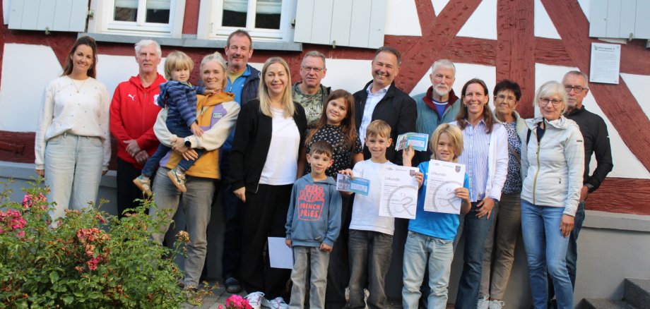 Gruppenfoto der Teilnehmerinnen und Teilnehmer des Waldsolmser Stadtradelns mit Kindern und Erwachsenen vor einem Fachwerkhaus. Einige halten Urkunden und Auszeichnungen in die Kamera.